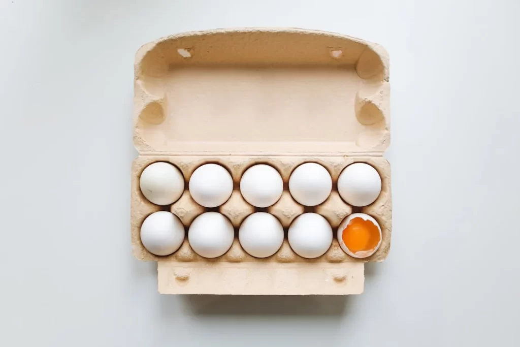 Egg carton with a cracked double-yolk egg.