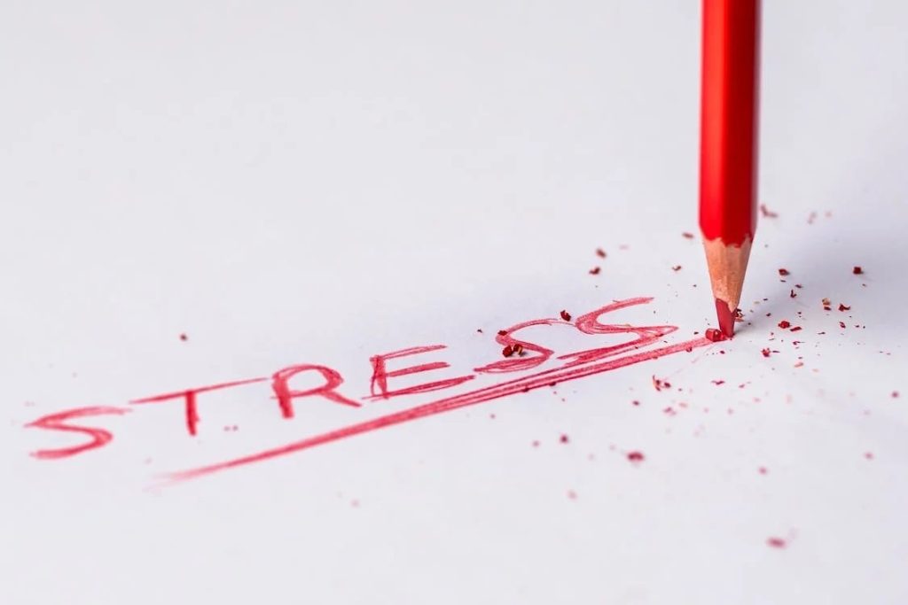 A broken red pencil writing the word 'STRESS' on paper, representing emotional pressure and the need for astrology and stress management techniques