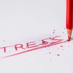 A broken red pencil writing the word 'STRESS' on paper, representing emotional pressure and the need for astrology and stress management techniques