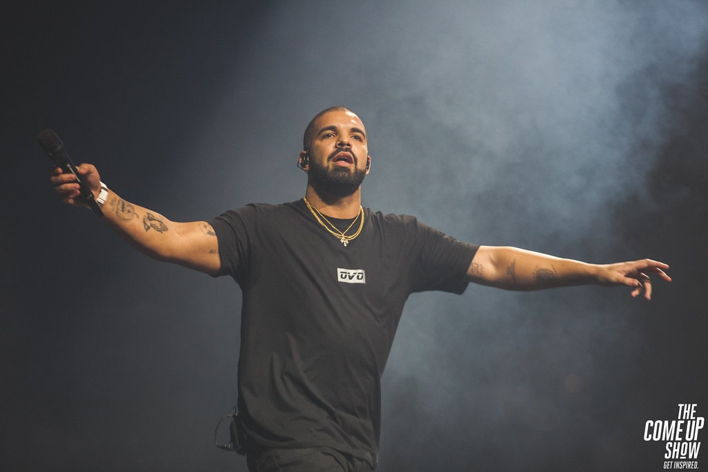 Drake actuando en vivo en el escenario, mostrando su presencia más grande que la vida en la batalla de Drake vs Kendrick